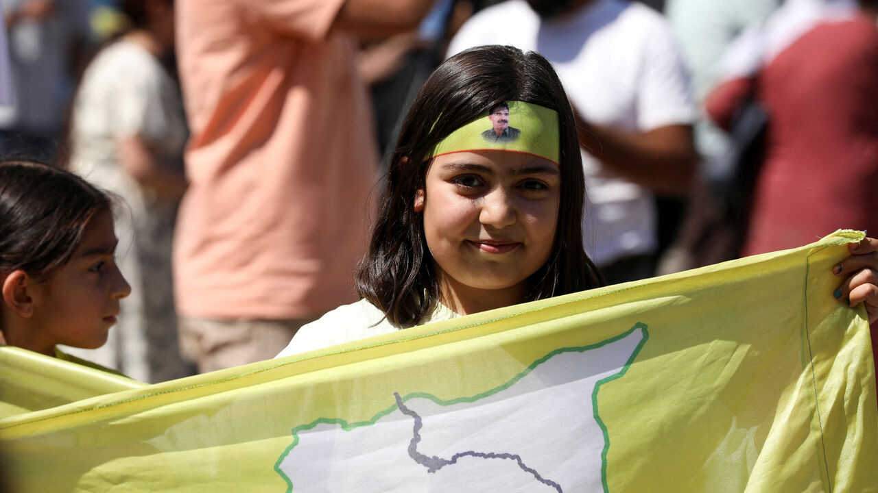 FILE PHOTO: A girl holds a Syrian Democratic Forces (SDF) flag during a demonstration under the slogan "With our will, we will protect our revolution”, in Qamishli, Syria September 17, 2025. REUTERS/Orhan Qereman/File Photo