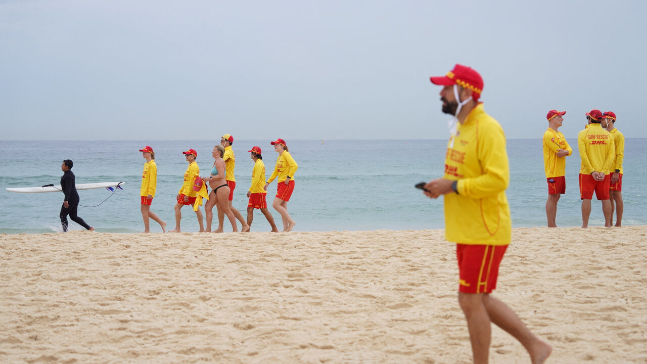 Members of Bondi Surf Life Saving Club and North Bondi Surf Life Saving Club walk on Bondi Beach during an event to stand shoulder to shoulder as they observe three minutes of silence to honour victims, responders, and lifesavers following the mass shooting that targeted a Jewish Hanukkah celebration at Bondi Beach on December 14, in Sydney, Australia, December 20, 2025. REUTERS/Audrey Richardson