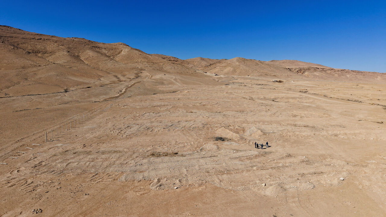 FILE PHOTO: Four people walk through the desert mass grave created under the Assad government near the town of Dhumair, Syria, February 27, 2025. REUTERS/Khalil Ashawi/File Photo