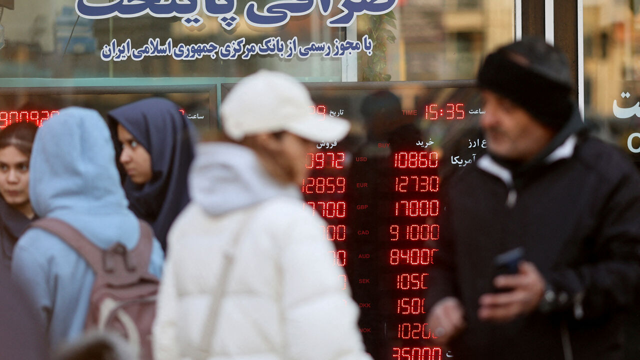 FILE PHOTO: People walk past a display sign at a currency exchange bureau as the value of the Iranian rial drops, in Tehran, Iran, December 20, 2025. Majid Asgaripour/WANA (West Asia News Agency) via REUTERS/File Photo