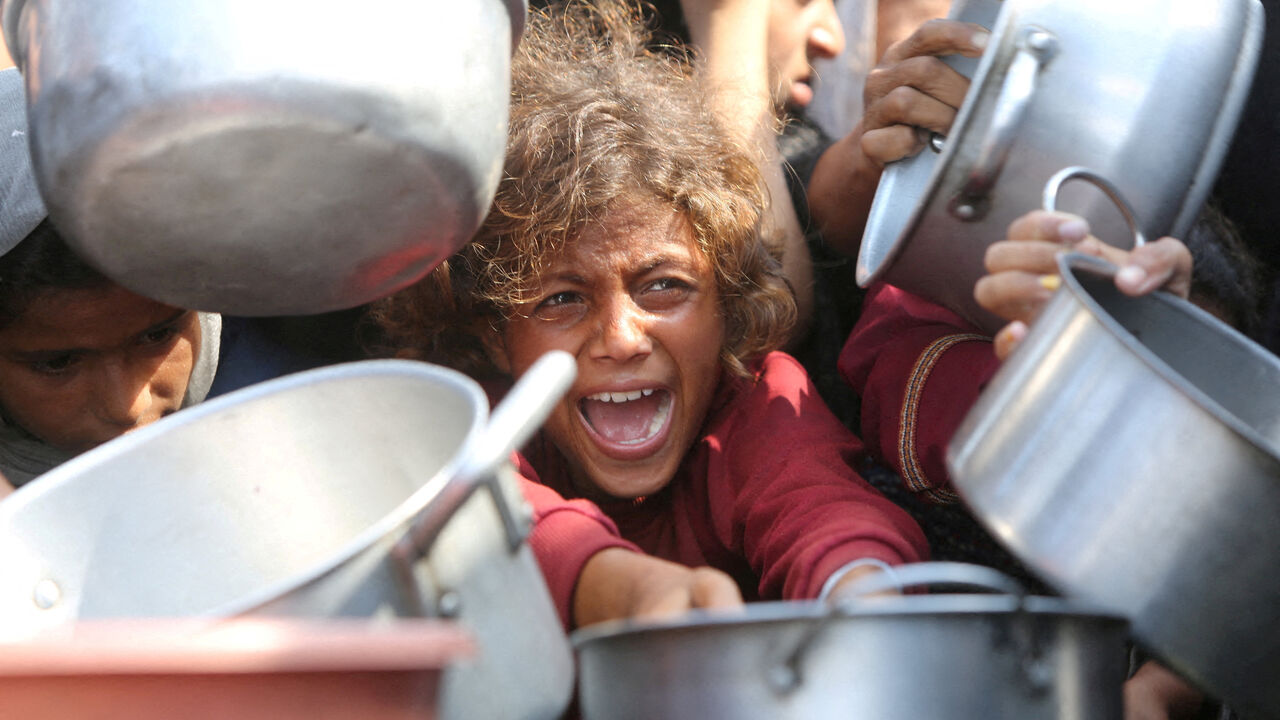 FILE PHOTO: A child reacts surrounded by pots as Palestinians wait to receive food from a charity kitchen in Khan Younis, southern Gaza Strip, August 21, 2025. REUTERS/Hatem Khaled/File Photo