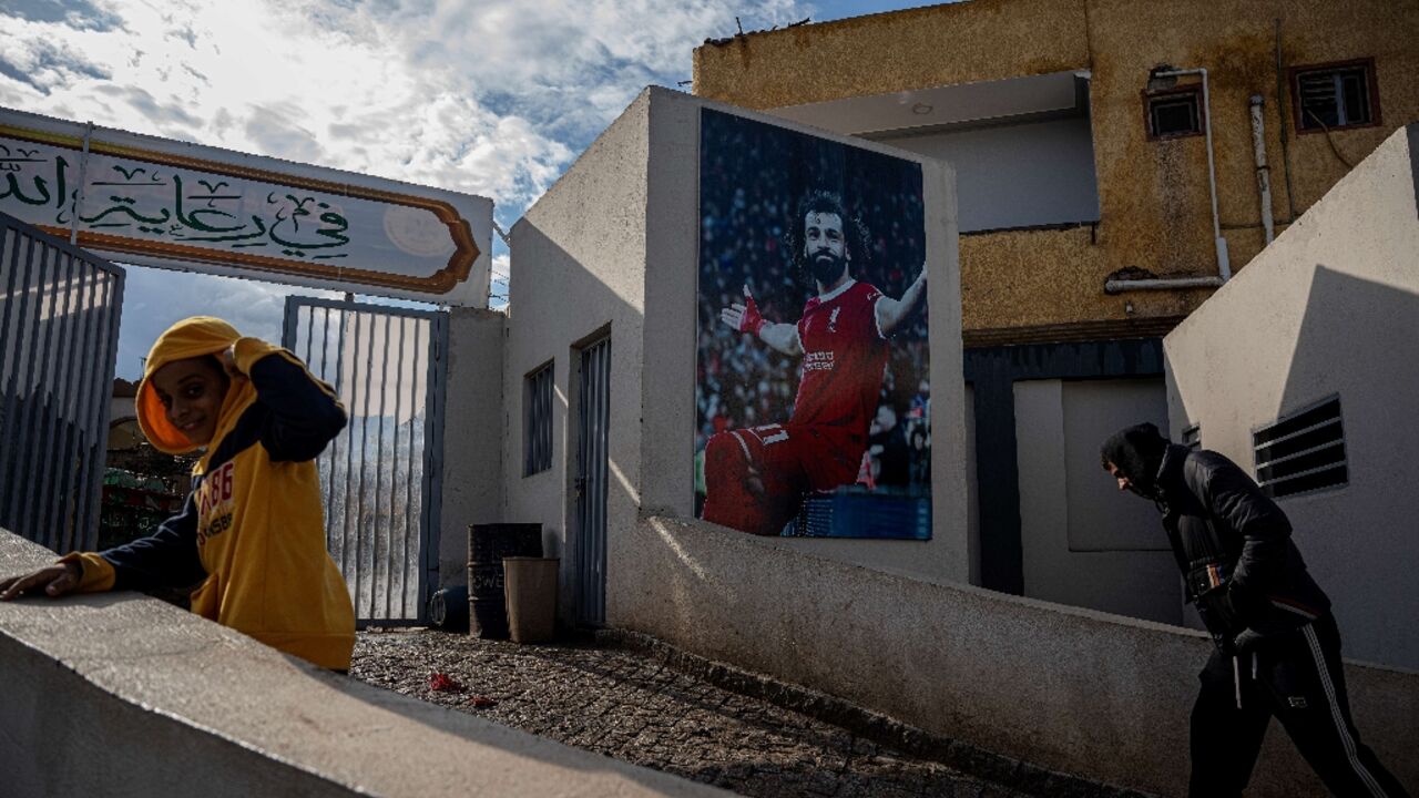 Locals pass a mural of Mohamed Salah at the entrance to the sports complex in his Egyptian home village of Nagrig
