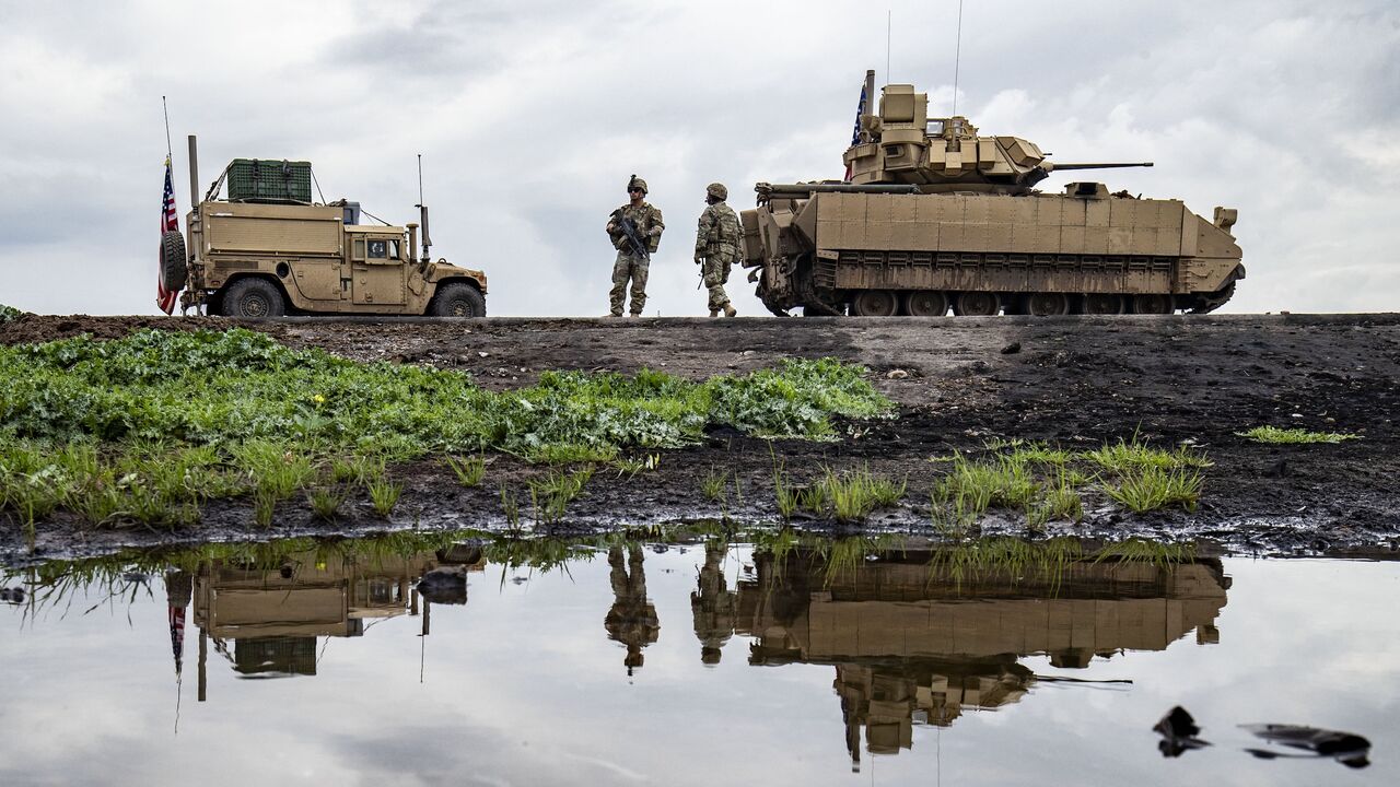 US Army soldiers stand near armored military vehicles on the outskirts of Rumaylan in Syria's northeastern Hasakah province, bordering Turkey, on March 27, 2023.