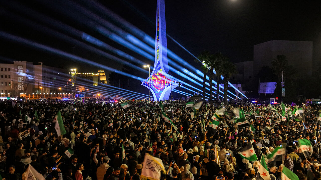TOPSHOT - This aerial view shows people gathering to commemorate the 14th anniversary of the uprising against Syria's former president Bashar al-Assad for the first time since he was toppled in the Umayyad Square in the centre of Damascus on March 15, 2025. The rally in Damascus was the capital's first after years of repression under Assad, during which the square was the sole preserve of the ousted president's supporters. Activists called on people to hold similar demonstrations in the major cities of Homs