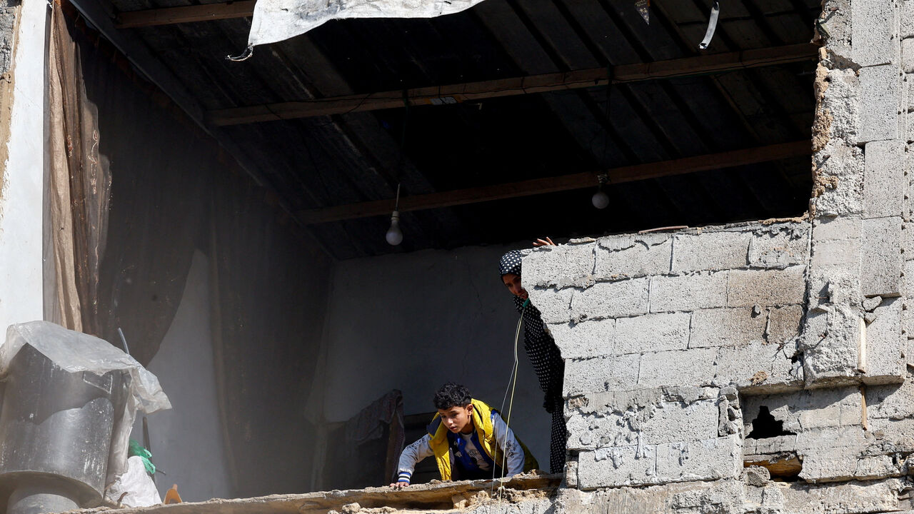 Palestinians look out from a building at the site of a collapsed house that was damaged during the war by an Israeli strike, in the central Gaza Strip, January 5, 2026. REUTERS/Mahmoud Issa
