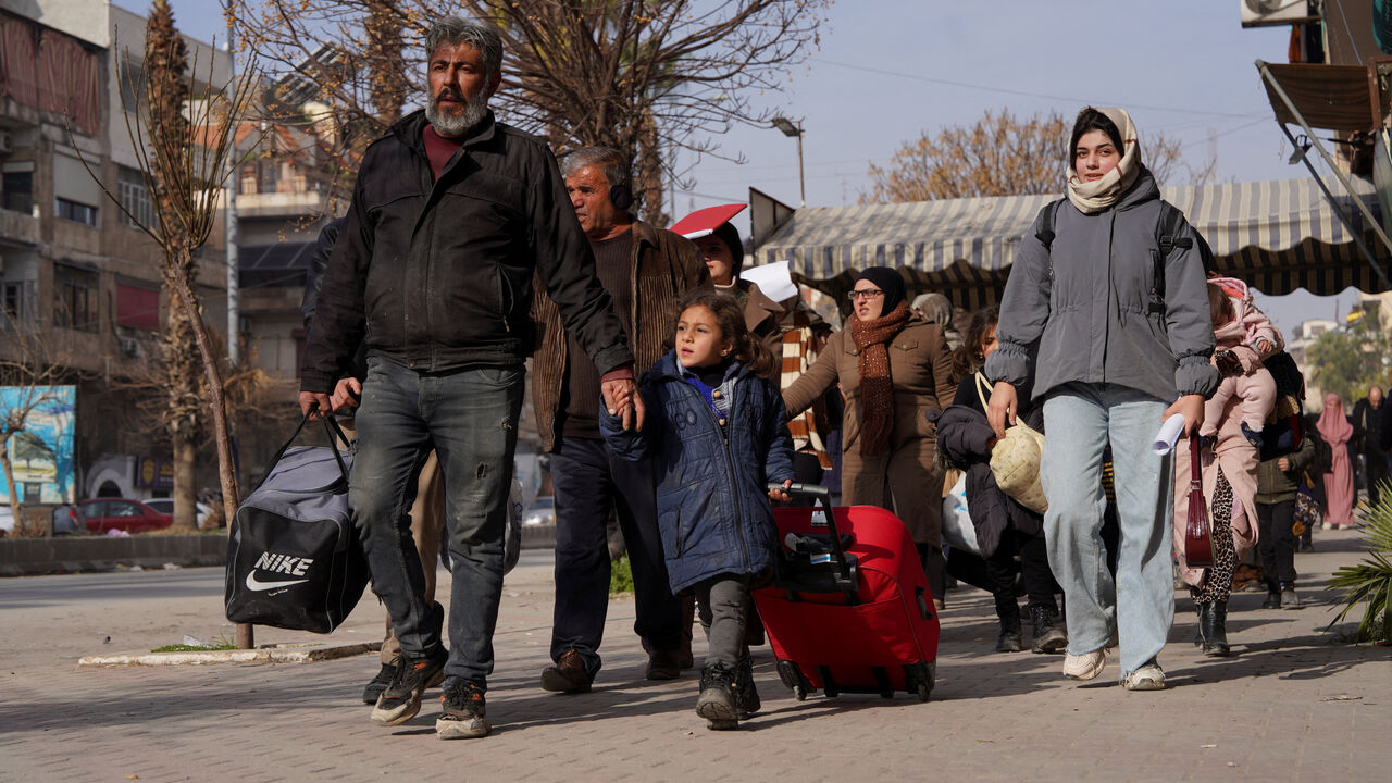 A group of civilians carry bags and belongings as they flee following renewed clashes between the Syrian army and the Syrian Democratic Forces (SDF), in Aleppo, Syria, January 7, 2026. REUTERS/Karam al-Masri