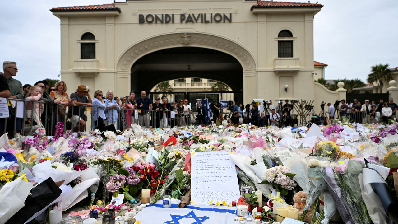 FILE PHOTO: People stand near flowers laid as a tribute at Bondi Beach to honour the victims of a mass shooting that targeted a Hanukkah celebration at Bondi Beach on Sunday, in Sydney, Australia, December 16, 2025. REUTERS/Flavio Brancaleone/File Photo