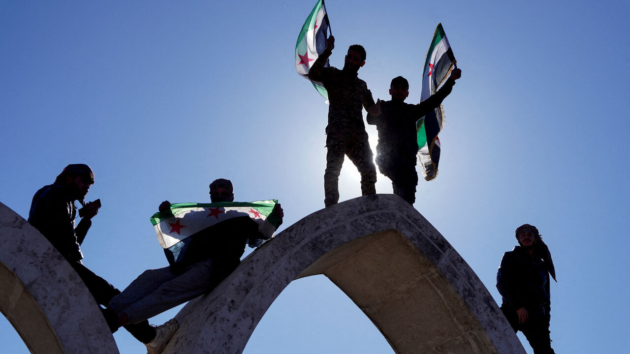 People hold flags as they celebrate, after Syria and the main Kurdish fighting force SDF struck a wide-ranging deal to bring Kurdish civilian and military authorities under central government control on Sunday, ending days of fighting in which Syrian troops captured territory including key oil fields, in Raqqa, Syria January 19, 2026. REUTERS/Karam al-Masri