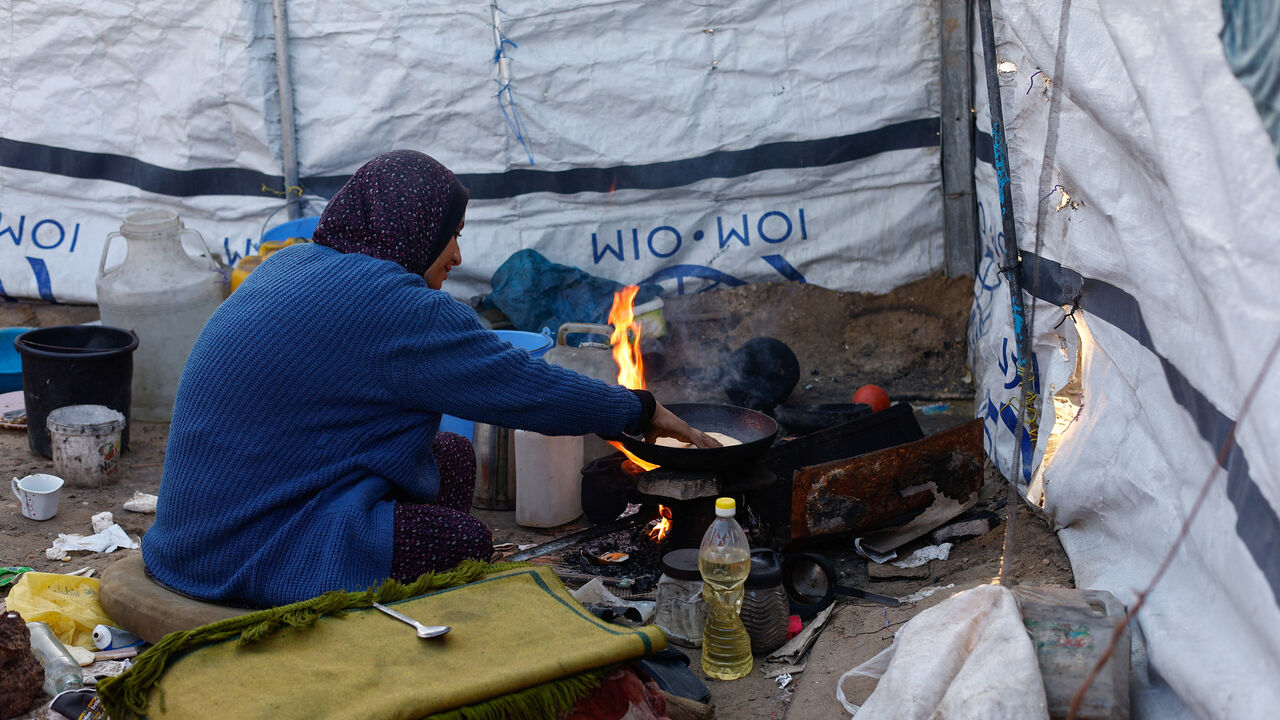 A woman cooks as displaced Palestinians shelter in a tent camp in Deir al-Balah, central Gaza Strip, January 19, 2026. REUTERS/Mahmoud Issa