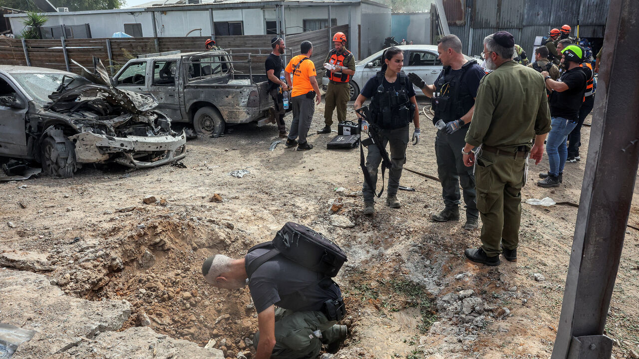 A security official investigates the crater formed when a projectile landed, after Hamas' armed wing said it attacked Tel Aviv with a missile salvo, amid the ongoing Israel-Hamas conflict, in Kfar Chabad, Israel, October 7, 2024. REUTERS/Itai Ron/File Photo