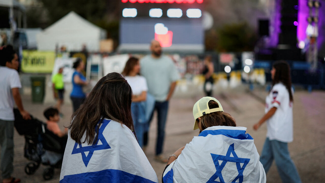 FILE PHOTO: Women wrapped in Israeli flags stand in front of a clock counting the days since the deadly October 7, 2023, Hamas attack, at "Hostages Square" in Tel Aviv, Israel, October 14, 2025, following the release of hostages after a ceasefire between Israel and Hamas went into effect. REUTERS/Stoyan Nenov/ File Photo