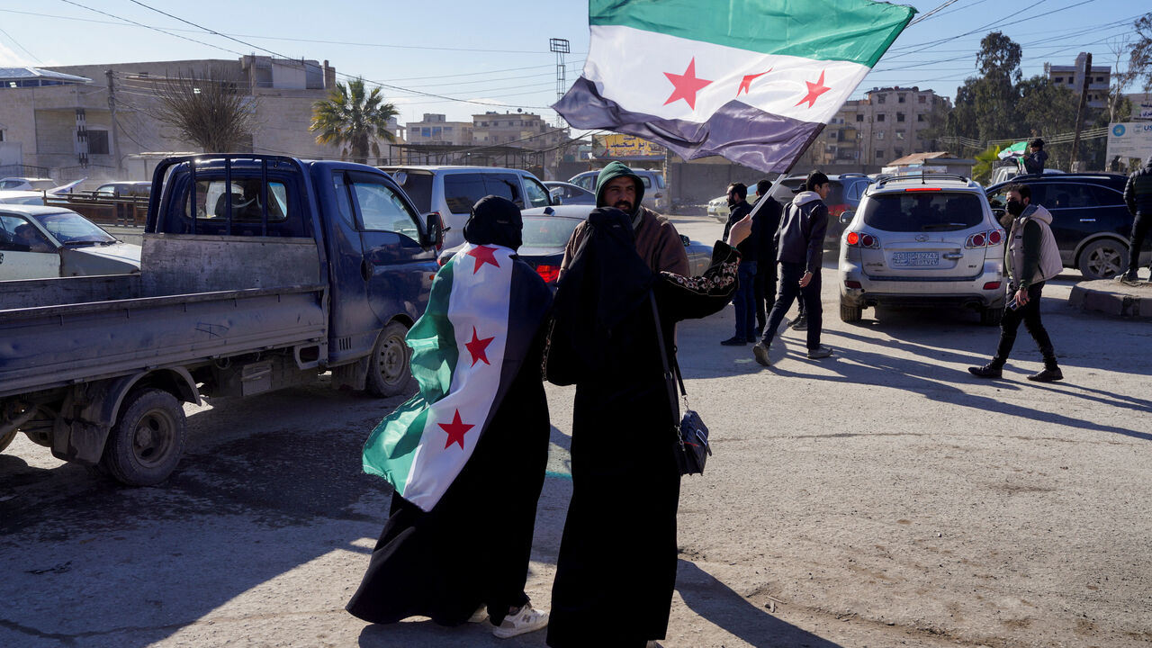 Women walk with Syrian flags, after Syria and the main Kurdish fighting force SDF struck a wide-ranging deal to bring Kurdish civilian and military authorities under central government control on Sunday, ending days of fighting in which Syrian troops captured territory including key oil fields, in Raqqa, Syria January 19, 2026. REUTERS/Karam al-Masri