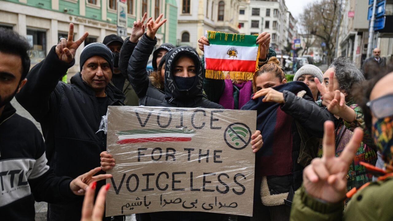 Protesters hold a placard reading "Voice for the voiceless" and the flag of Iran from before the 1979 revolution during a demonstration outside the Iranian Consulate in Istanbul