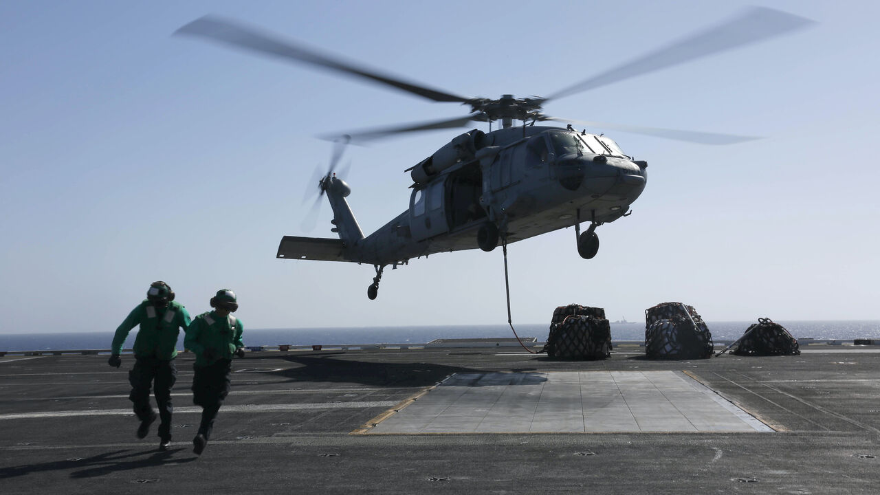 In this handout photo provided by the US Navy, Logistics Specialist 1st Class Ousseinou Kaba (left), from Silver Spring, Md., and Logistics Specialist Seaman Abigail Marshke, from Flint, Mich., attach cargo to an MH-60S Sea Hawk helicopter from the "Nightdippers" of Helicopter Sea Combat Squadron (HSC) 5 from the flight deck of the Nimitz-class aircraft carrier USS Abraham Lincoln (CVN 72) May 10, 2019 in the Red Sea. 