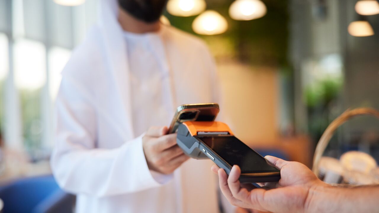 The close-up of a phone tapping a POS at the coffee shop highlights the ease of contactless transactions.