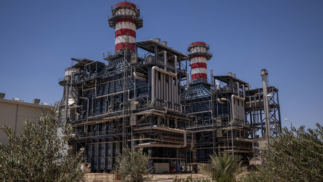Workers walk past the gas turbine and heat recovery system of Syria's largest power plant on June 12, 2025, in Deir Ali, Syria.