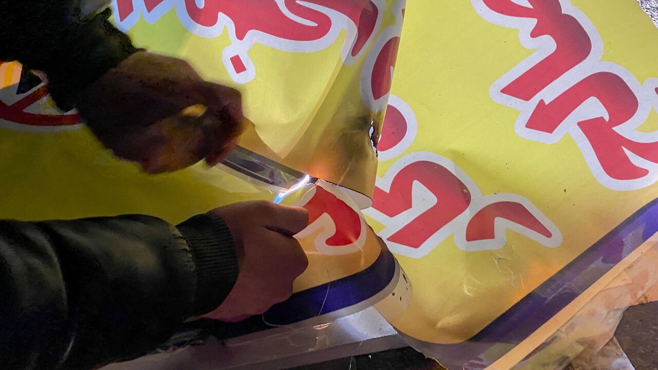 A person uses a lighter to set fire to a banner during demonstrations in Hamedan, Iran, on Jan. 1, 2026. 