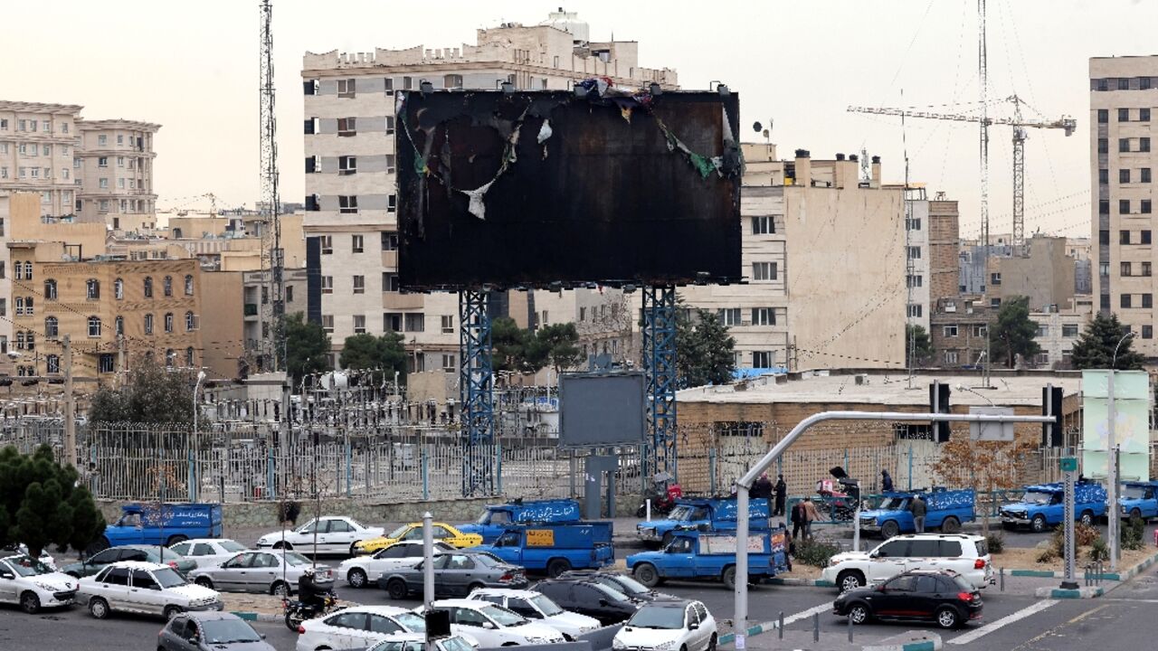 Vehicles drive past a burnt billboard as daily life returned to the streets of Iran's capital following nationwide protests