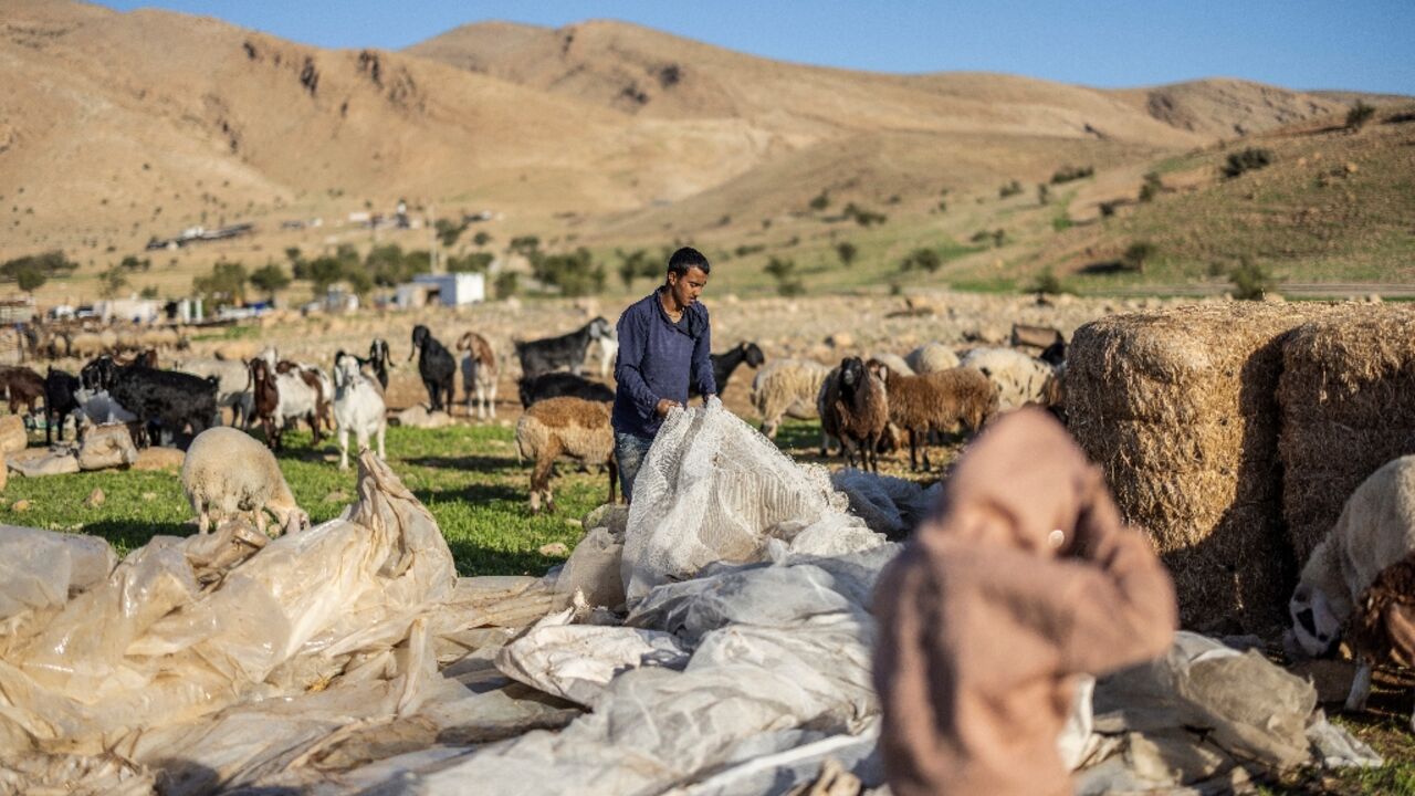 A Bedouin man gathers plastic sheeting as families begin to collect their belongings to leave their homes after harassment from Israeli settlers in Ras Ein al-Auja