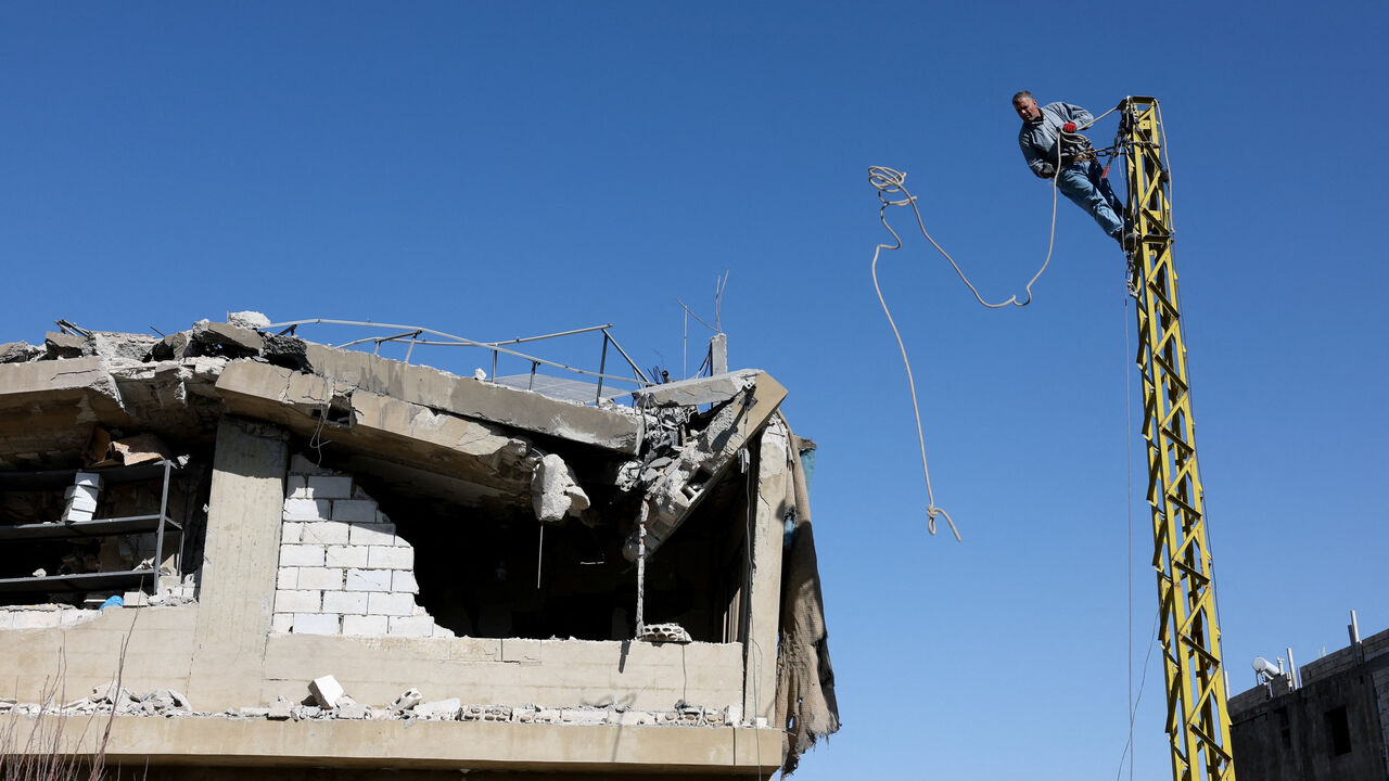 A man works on an electric pole next to a damaged building, in the aftermath of an Israeli strike on friday, in Tamnine el Tahta, Bekaa valley, Lebanon, February 21, 2026. REUTERS/Mohamed Azakir