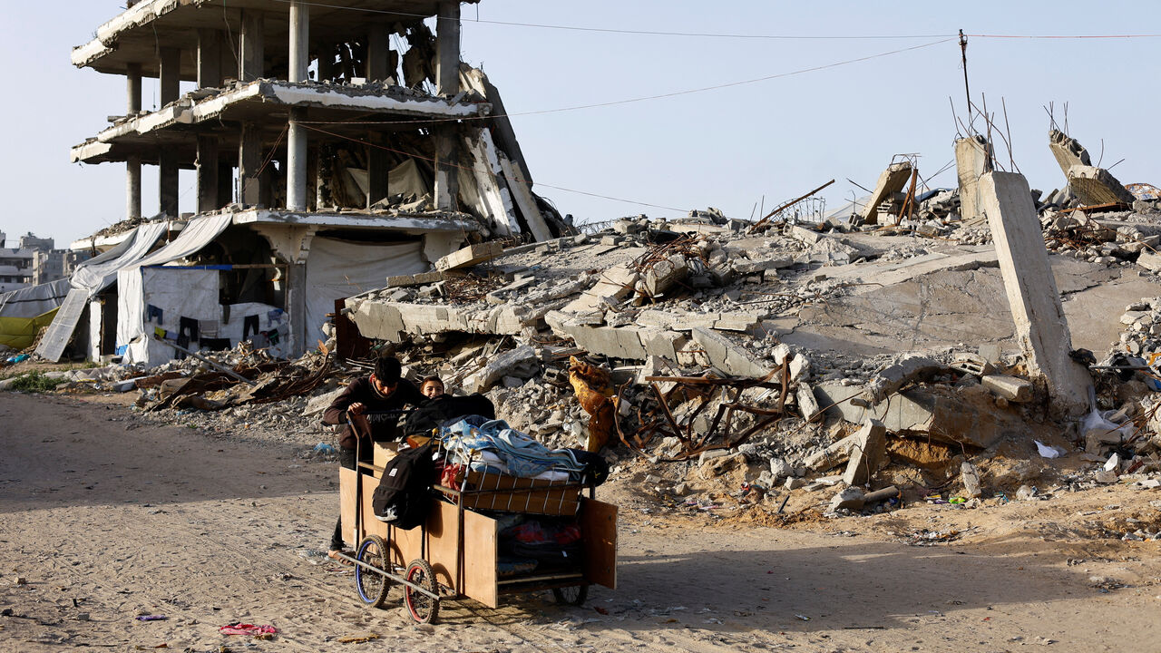 Palestinians push a cart past the rubble of residential buildings destroyed during the two-year Israeli offensives, in Gaza City, February 17, 2026. REUTERS/Mahmoud Issa