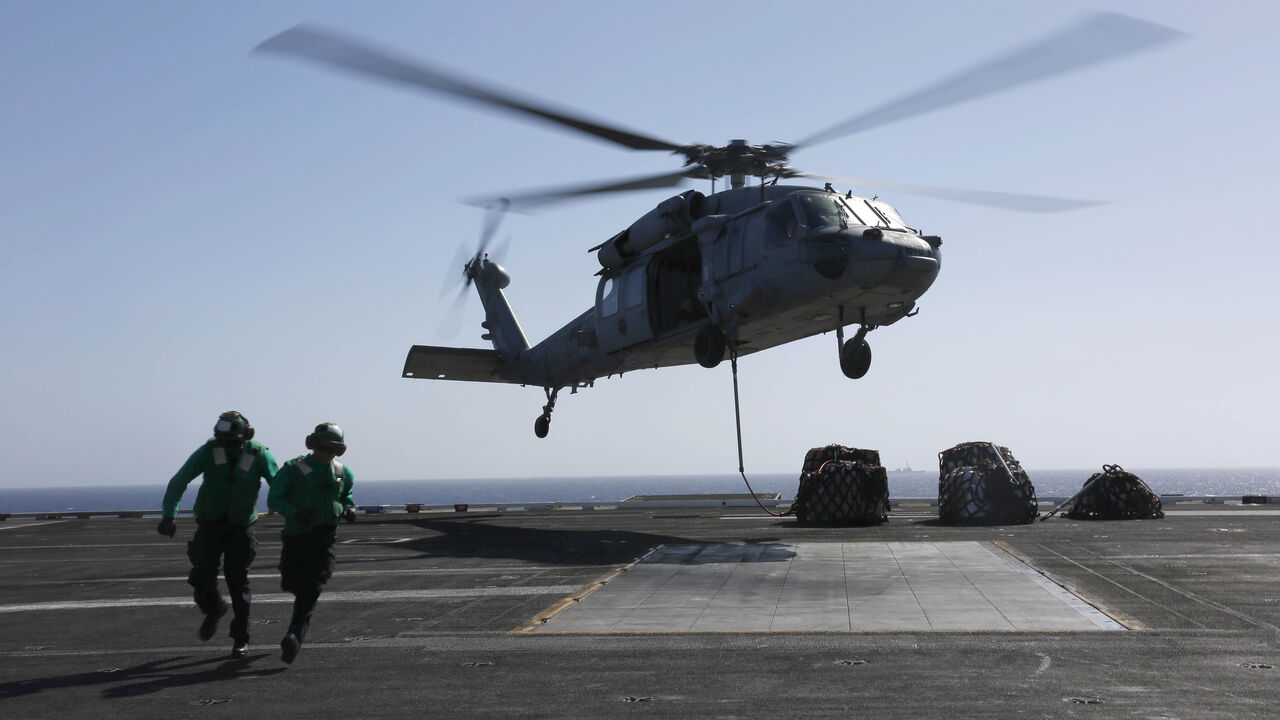 In this handout photo provided by the US Navy, Logistics Specialist 1st Class Ousseinou Kaba (left), from Silver Spring, Md., and Logistics Specialist Seaman Abigail Marshke, from Flint, Mich., attach cargo to an MH-60S Sea Hawk helicopter from the "Nightdippers" of Helicopter Sea Combat Squadron (HSC) 5 from the flight deck of the Nimitz-class aircraft carrier USS Abraham Lincoln (CVN 72) May 10, 2019 in the Red Sea.