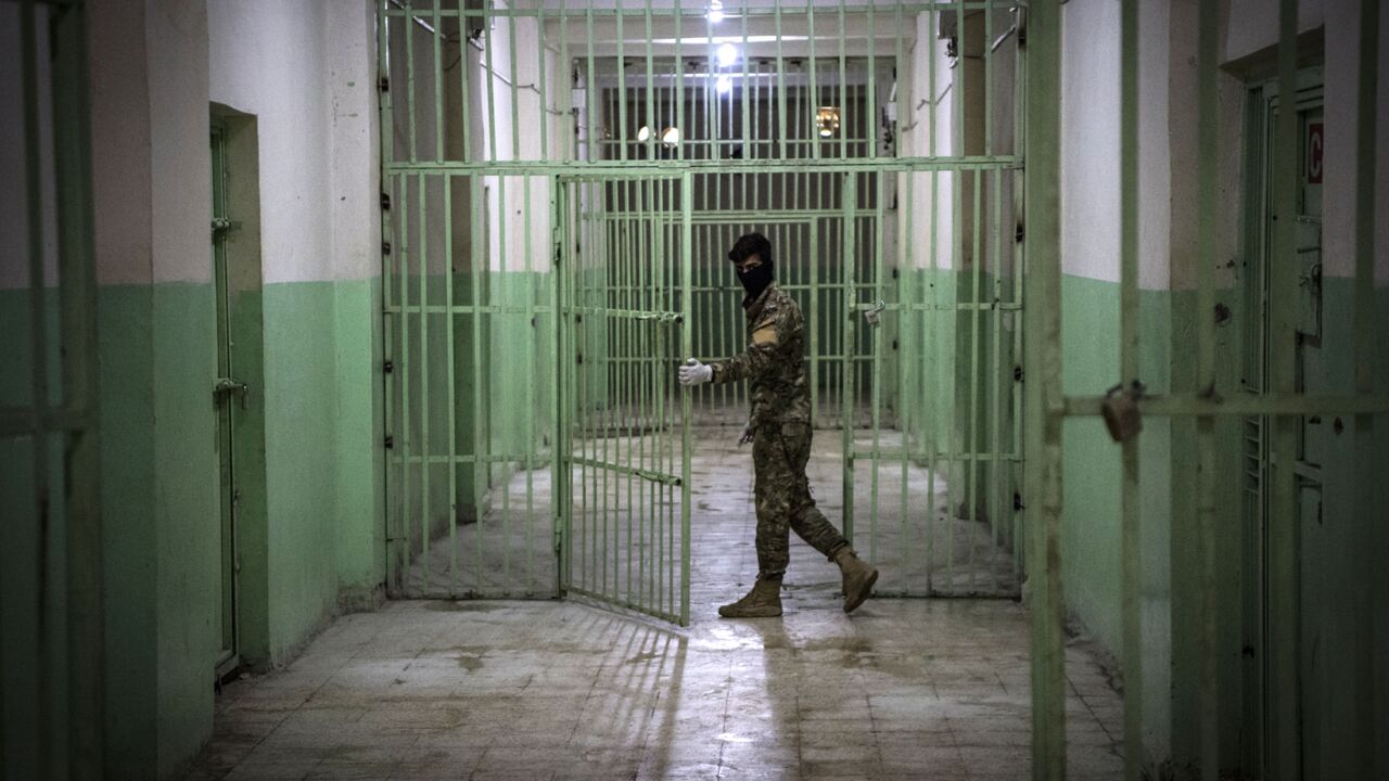 A member of the Syrian Democratic Forces (SDF) stands guard in a prison where men suspected to be afiliated with the Islamic State (IS) group are jailed in northeast Syria in the city of Hasakeh on Oct. 26, 2019. 