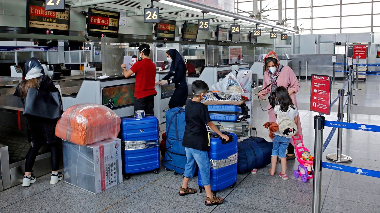 Outbound passengers arrive with their luggage at the Emirates check-in counter at the Iranian capital Tehran's Imam Khomeini International Airport, on July 17, 2020.