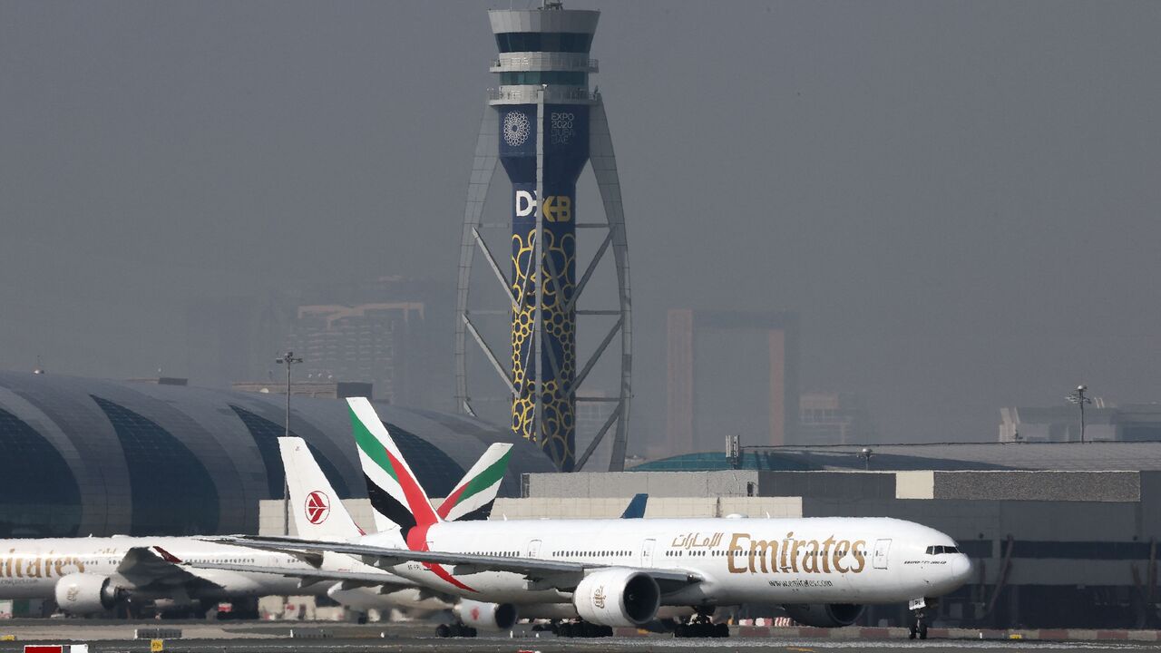 An Emirates Boing 777-300ER is pictured in front an air traffic control tower at Dubai International Airport in Dubai, on Jan. 30, 2023.