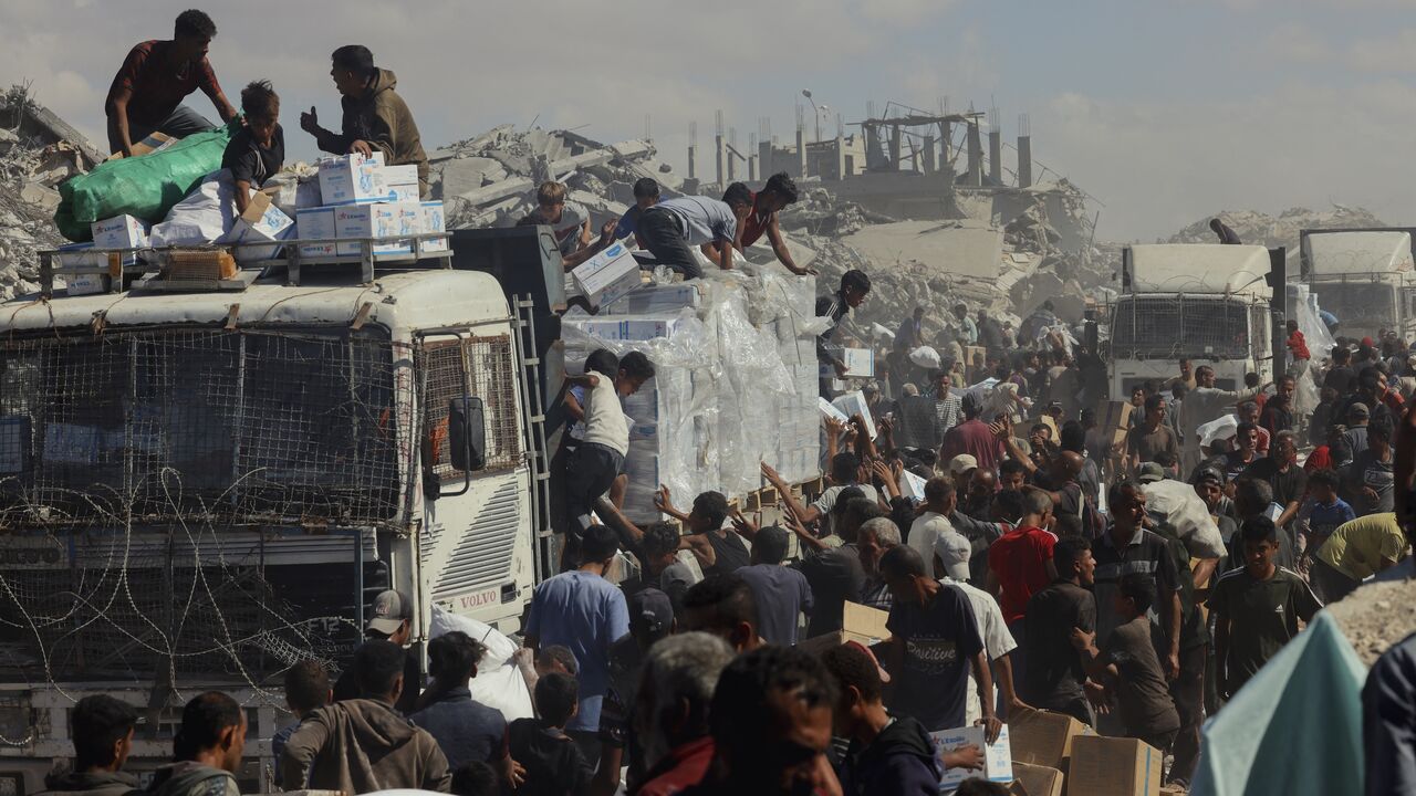 People walk through a heavily damaged street in Khan Younis, southern Gaza Strip, on Oct. 12, 2025.