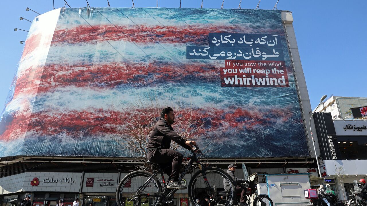 A cyclist rides past an anti-US billboard installed on a building along a street in Tehran on Feb. 26, 2026.