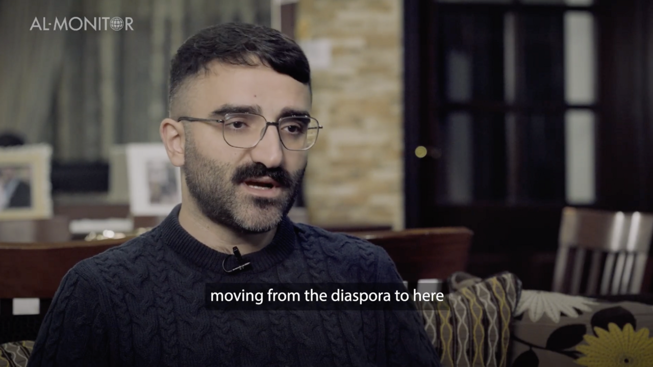 Iraqi Christian man in dark blue sweater sitting in an office 