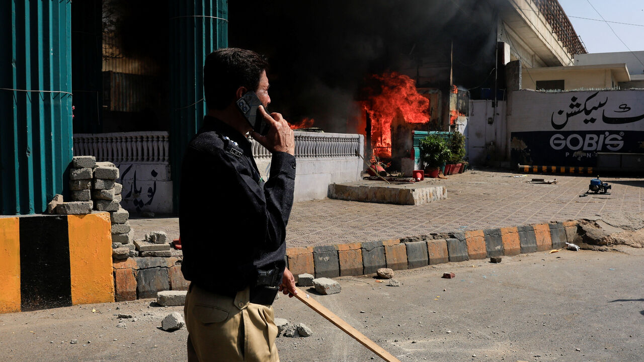 A police officer walks next to a checkpost set ablaze in a protest outside the U.S. Consulate General, following news of U.S. and Israeli strikes on Iran that killed supreme leader Ayatollah Ali Khamenei, in Karachi, Pakistan March 1, 2026. REUTERS/Akhtar Soomro