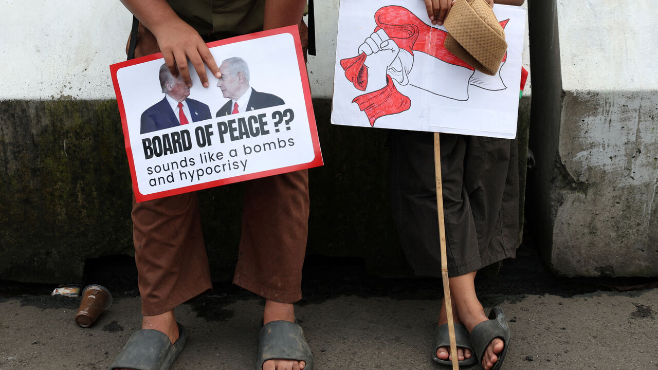 Boys in solidarity with Palestinians hold signs as they take part in a protest, outside the U.S. embassy, against Israel and demanding that the Indonesian government cancel the proposed multinational peacekeeping force for Gaza, following  Indonesia's President Prabowo Subianto invitation to Washington later this month for the first meeting of U.S. President Donald Trump's Board of Peace, in Jakarta, Indonesia, February 13, 2026. REUTERS/Ajeng Dinar Ulfiana