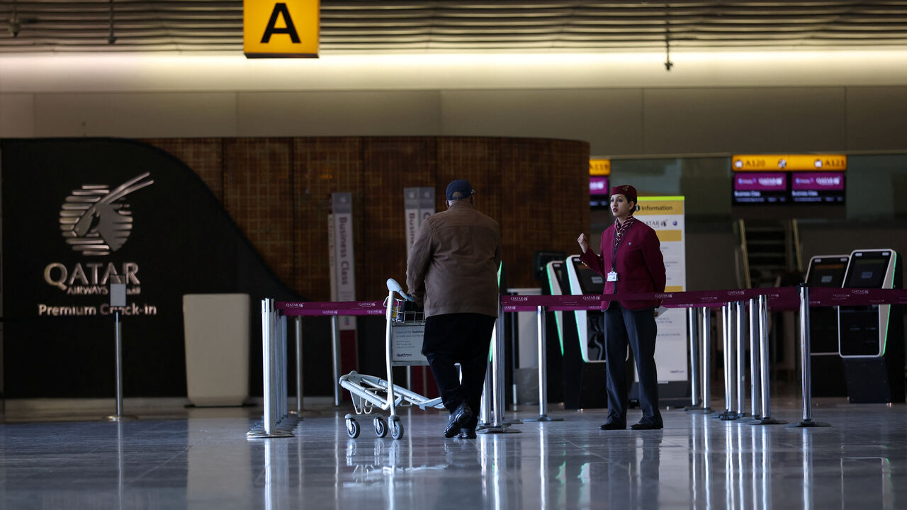An employee of Qatar Airways informs a traveller at a closed check-in area amid the U.S.-Israel conflict with Iran, at Heathrow Airport Terminal 4, in Greater London, Britain, March 2, 2026. REUTERS/Isabel Infante
