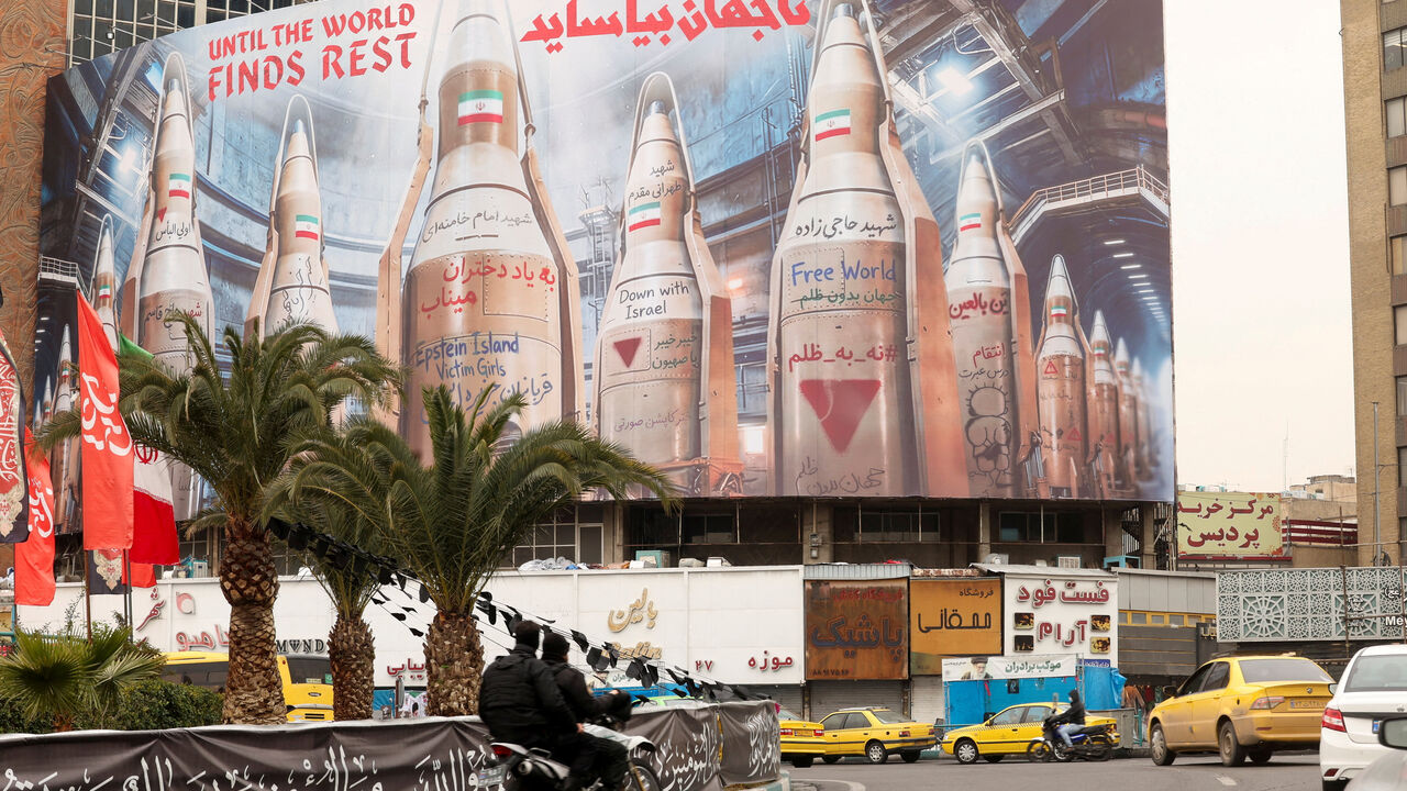 People on motorcycles ride past a large billboard with images of Iranian missiles, amid the U.S.-Israeli conflict with Iran, in Tehran, Iran, March 15, 2026. REUTERS/Alaa Al-Marjani
