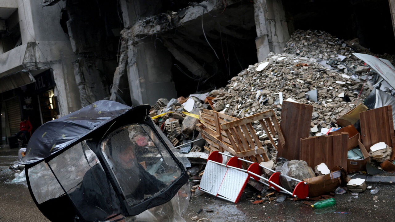 A man rides a scooter next to a damaged building in the aftermath of an Israeli strike in central Beirut, targeting what Israel said is a Hezbollah-affiliated bank, following an escalation between Hezbollah and Israel amid the U.S.-Israeli conflict with Iran, in Beirut, Lebanon, March 15, 2026. REUTERS/Claudia Greco