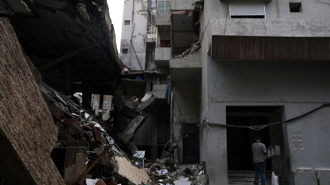 A man carries a ladder next to a damaged building in the aftermath of an Israeli strike in central Beirut, targeting what Israel said is a Hezbollah-affiliated bank, following an escalation between Hezbollah and Israel amid the U.S.-Israeli conflict with Iran, in Beirut, Lebanon, March 15, 2026. REUTERS/Claudia Greco