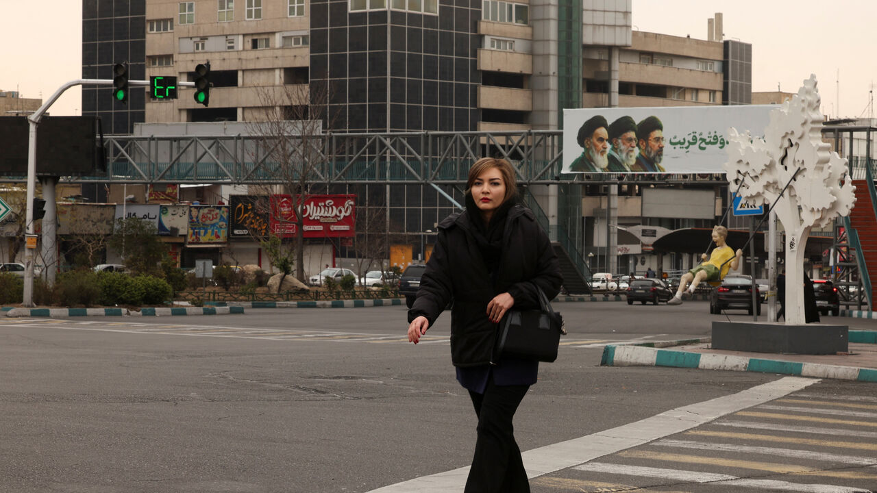 FILE PHOTO: A woman walks across the street, with a banner of all three leaders of Iran, late Ruhollah Khomeini, late Ayatollah Ali Khamenei, and Mojtaba Khamenei in the background, amid the US-Israeli conflict with Iran, in Tehran, Iran, March 15, 2026. REUTERS/Alaa Al-Marjani/File Photo
