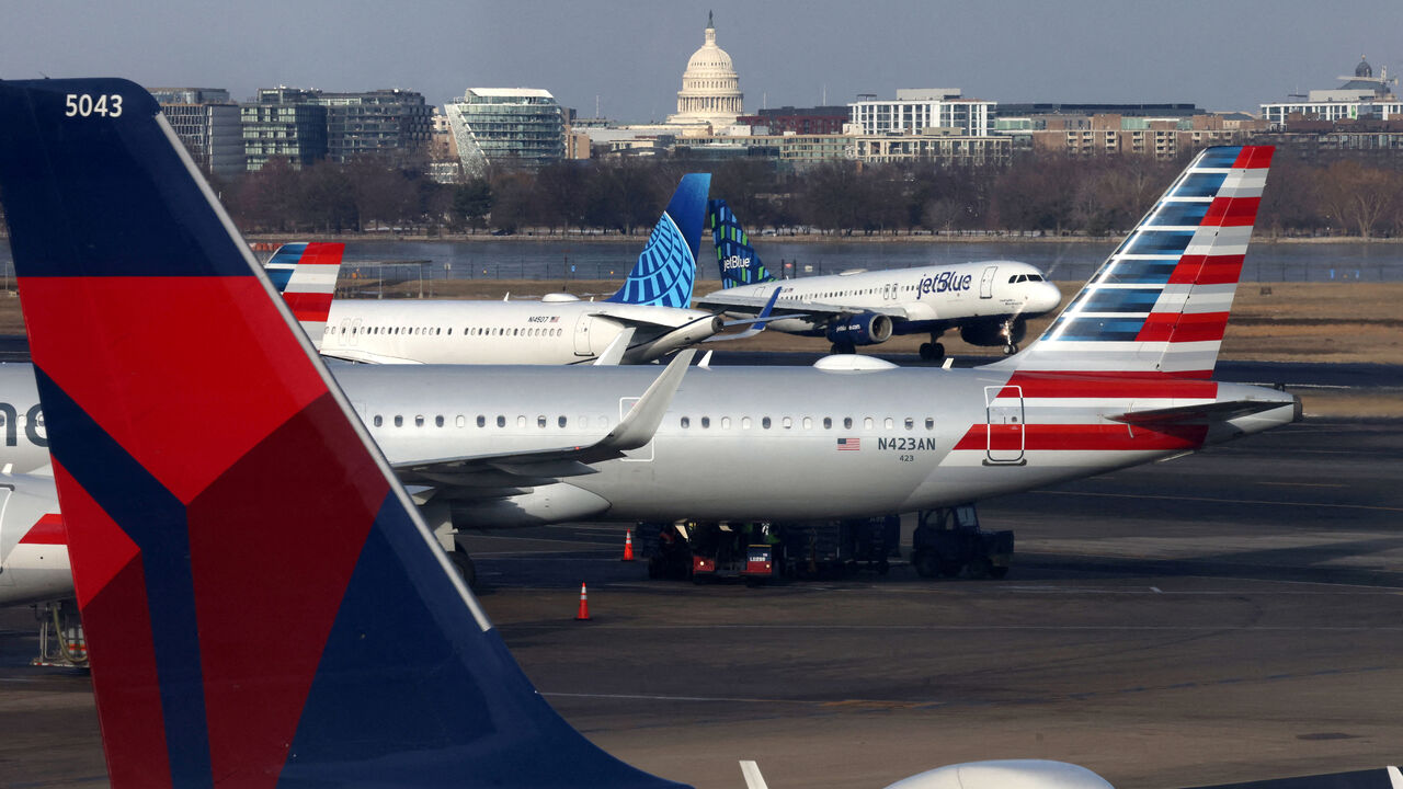 FILE PHOTO: A JetBlue aircraft lands under the DC skyline featuring the U.S. Capitol building, near United Airlines, American Airlines and Delta Airlines aircraft on the tarmac at Ronald Reagan Washington National Airport in Arlington, Virginia, U.S. January 25, 2025.  REUTERS/Jim Urquhart/File Photo