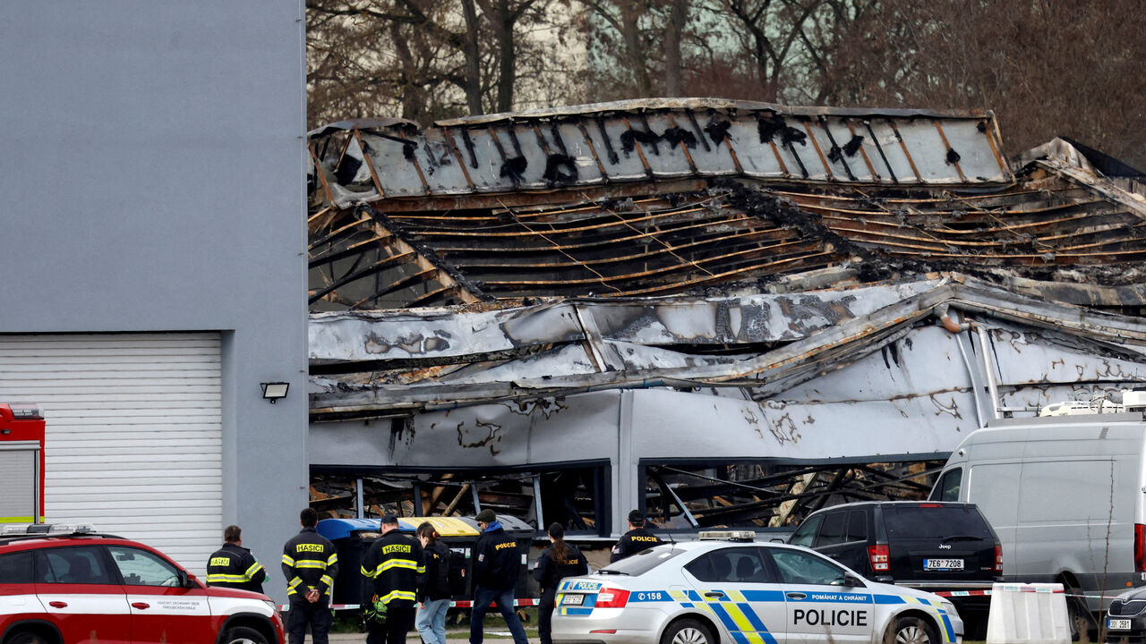 FILE PHOTO: Police officers and a firefighters stand in front of a burned production hall at an industrial area in Pardubice, Czech Republic, March 20, 2026. REUTERS/David W Cerny/File Photo