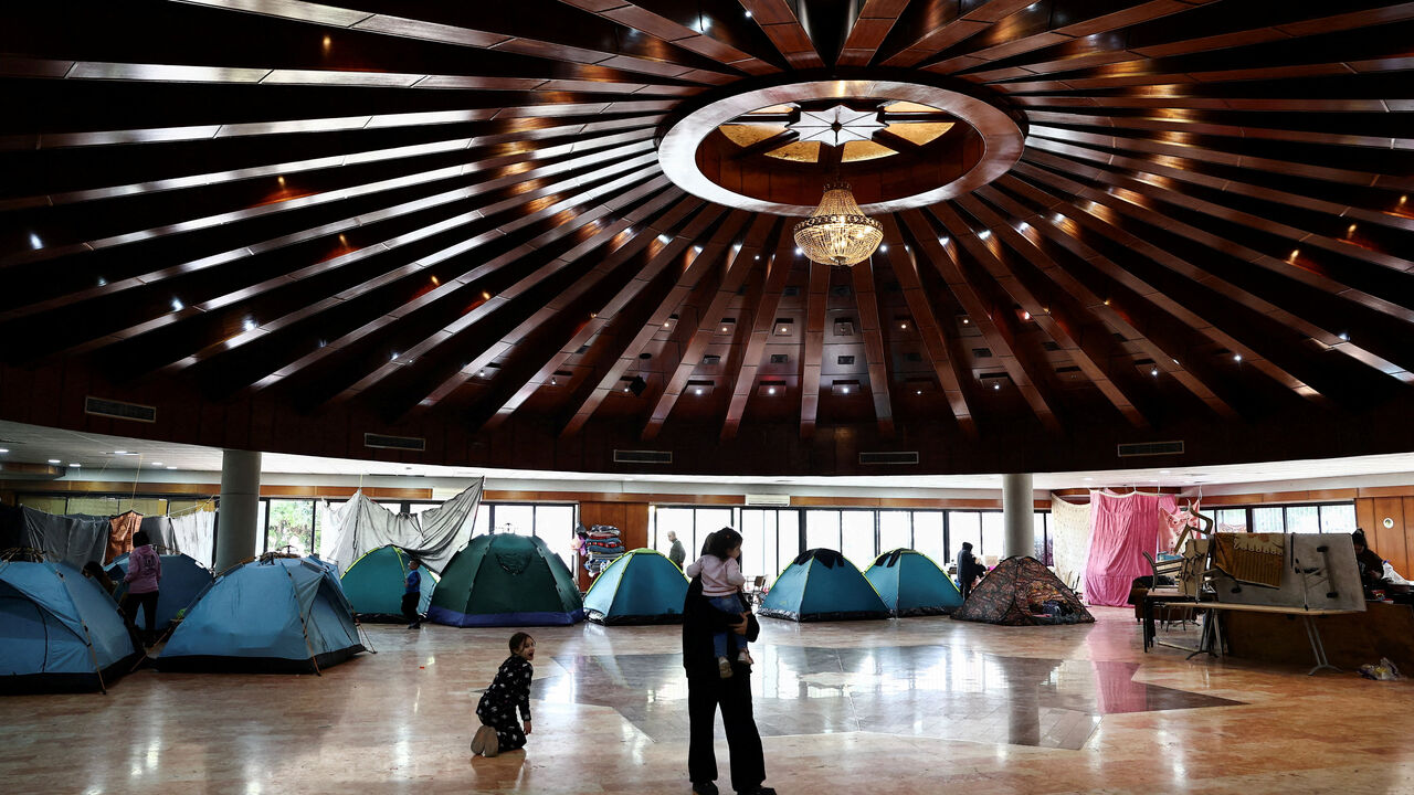 A woman holds a child in a school turned into a shelter for displaced families, amid escalating hostilities between Israel and Hezbollah, as the U.S.-Israeli conflict with Iran continues, in Dekwaneh, Lebanon. REUTERS/Yara Nardi