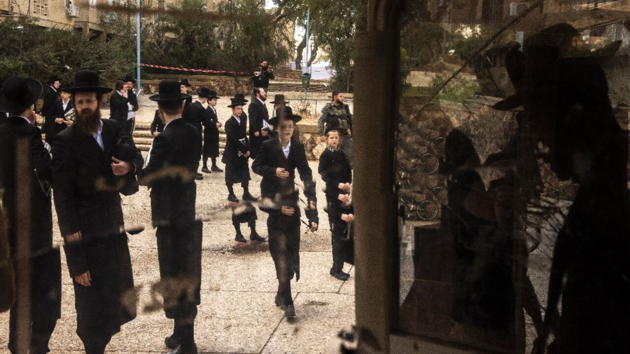 Israeli Orthodox Jews inspect the site of an Iranian missile strike in Arad on March 22