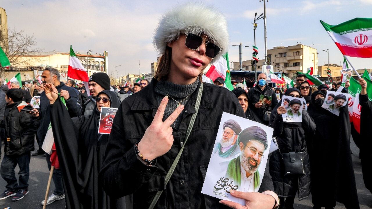 A woman holds a picture of Ayatollah Mojtaba Khamenei (R) and his late father Ali Khamenei