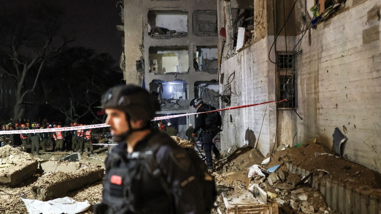 First responders inspect the site of an Iranian missile strike in Arad
