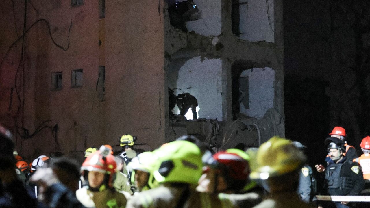 First responders inspect the site of an Iranian missile strike in Arad, Israel