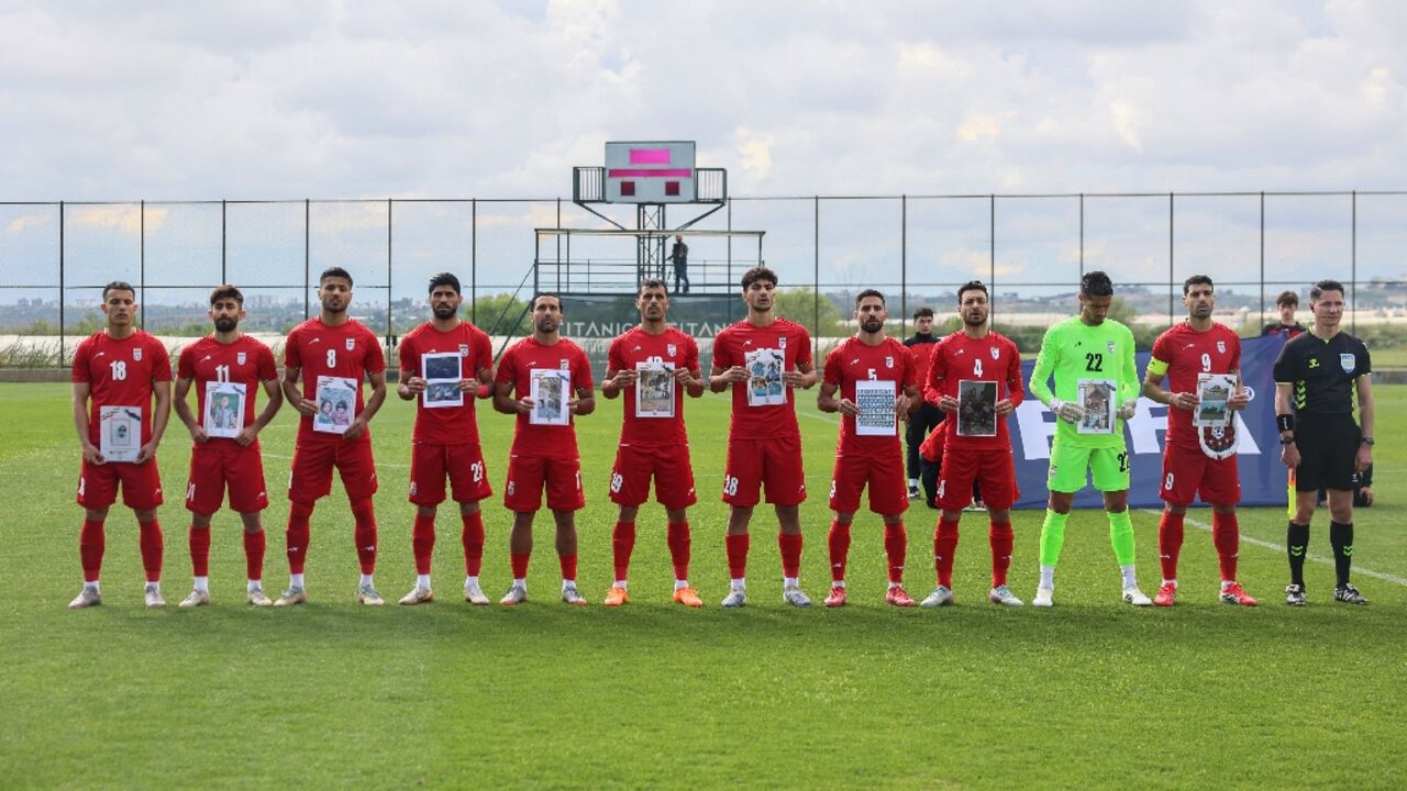 Iran players hold a photo of children said to have been killed in the Middle East war