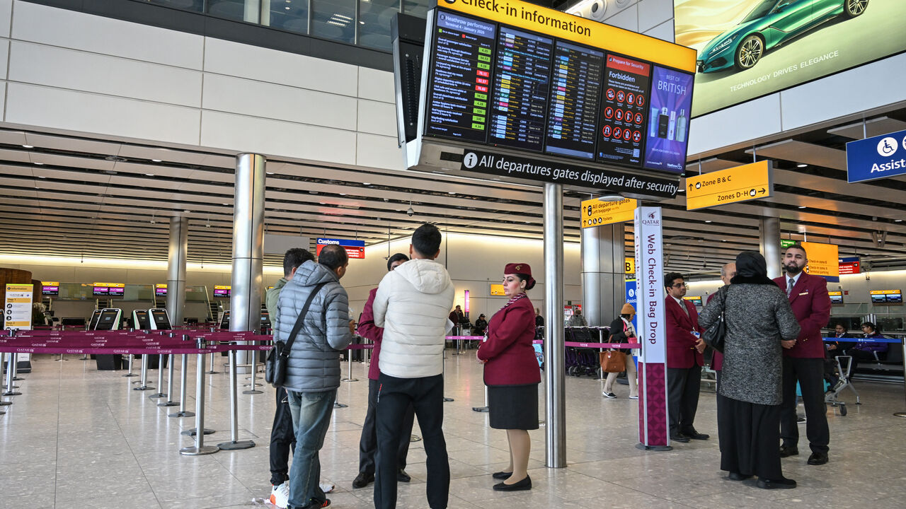 Staff from Qatar Airways help assist people with questions at their empty check-in area at London Heathrow Airport in west London on March 1, 2026, as flights are severely disrupted following the US and Israel's strikes on Iran. 