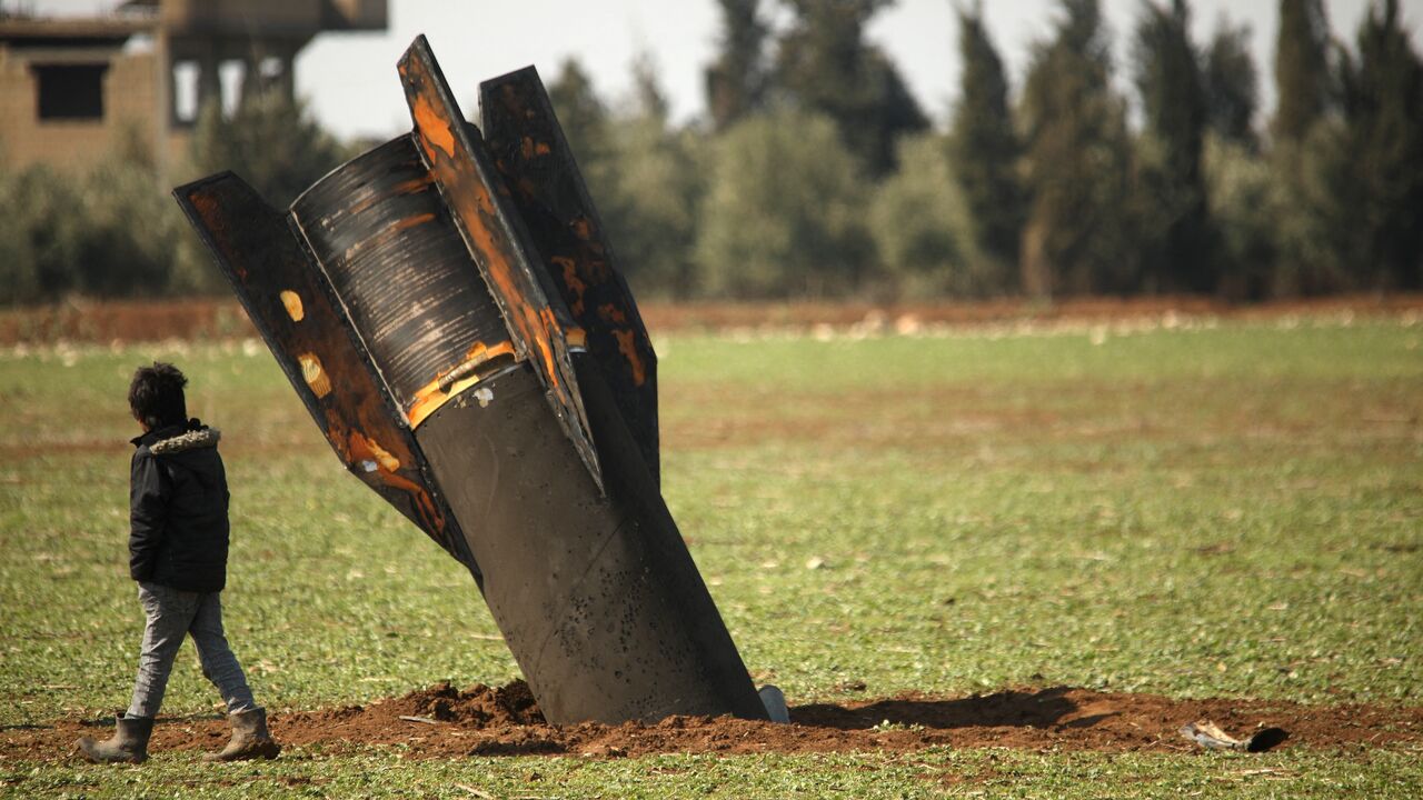 A boy walks past an unexploded missile that landed in an open field on the outskirts of Qamishli, eastern Syria, on March 5, 2026. 