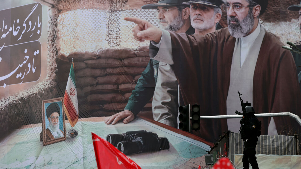An Iranian security force officer stands guard next to a huge billboard of Iran's newly nominated supreme leader Ayatollah Mojataba Khamenei (pointing) during Al-Quds (Jerusalem) Day rally, a commemoration in support of the Palestinian people on the last Friday of the Islamic holy month of Ramadan, in Tehran on March 13, 2026. On February 28, Israel and the United States launched strikes on Iran, killing its supreme leader Ayatollah Ali Khamenei (photo bottom L) and triggering a war that spread across the M